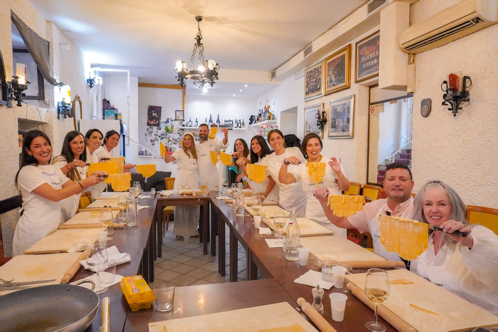 Gruppo di partecipanti mostra le fettuccine fatte a mano nella sala di Cucina Roma a Piazza Risorgimento