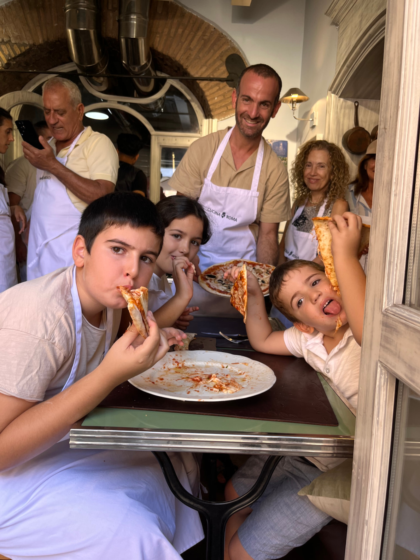 Famiglia e bambini gustano la pizza appena sfornata durante la pizza class a Roma di Cucina Roma